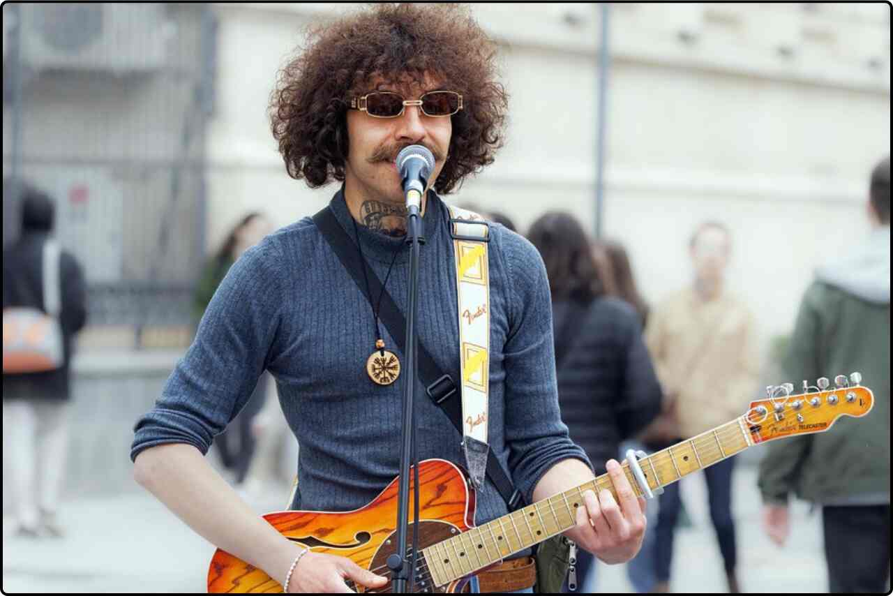 Musician busking with acoustic guitar in city environment